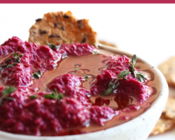 This is a side view of a speckled white bowl on a white counter. Inside the bowl is a pink beet dip topped with oil and fresh thyme leaves. Crackers are off to the side, next to the bowl on the white counter. Text overlay reads "horseradish beet dip".