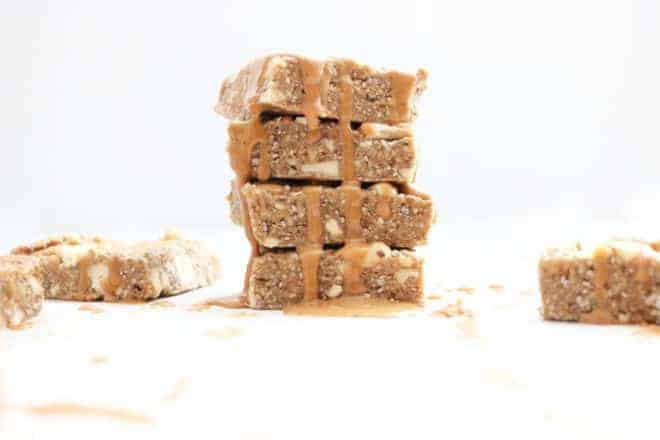 This is a stack of four bars drizzled with nut butter. This image is included in a roundup for 50+ healthy snacks. 
