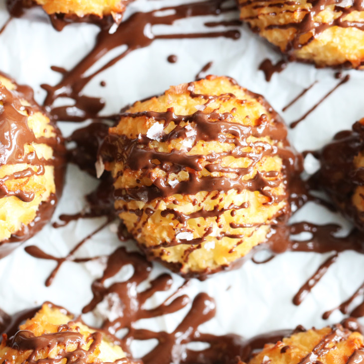 overhead image of coconut macaroons with melted chocolate drizzled on top on white background