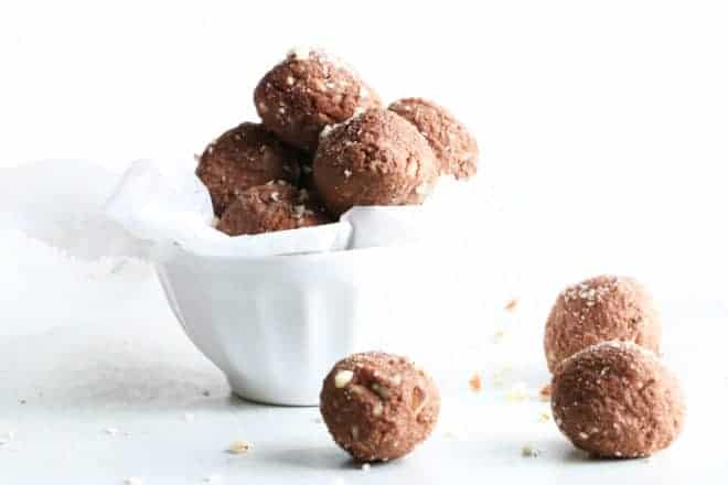 small white bowl filled with chocolate brazil nut energy bites on white counter and white background