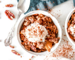 overhead image of four white ramekins with apple crisp and a scoop of vanilla ice cream
