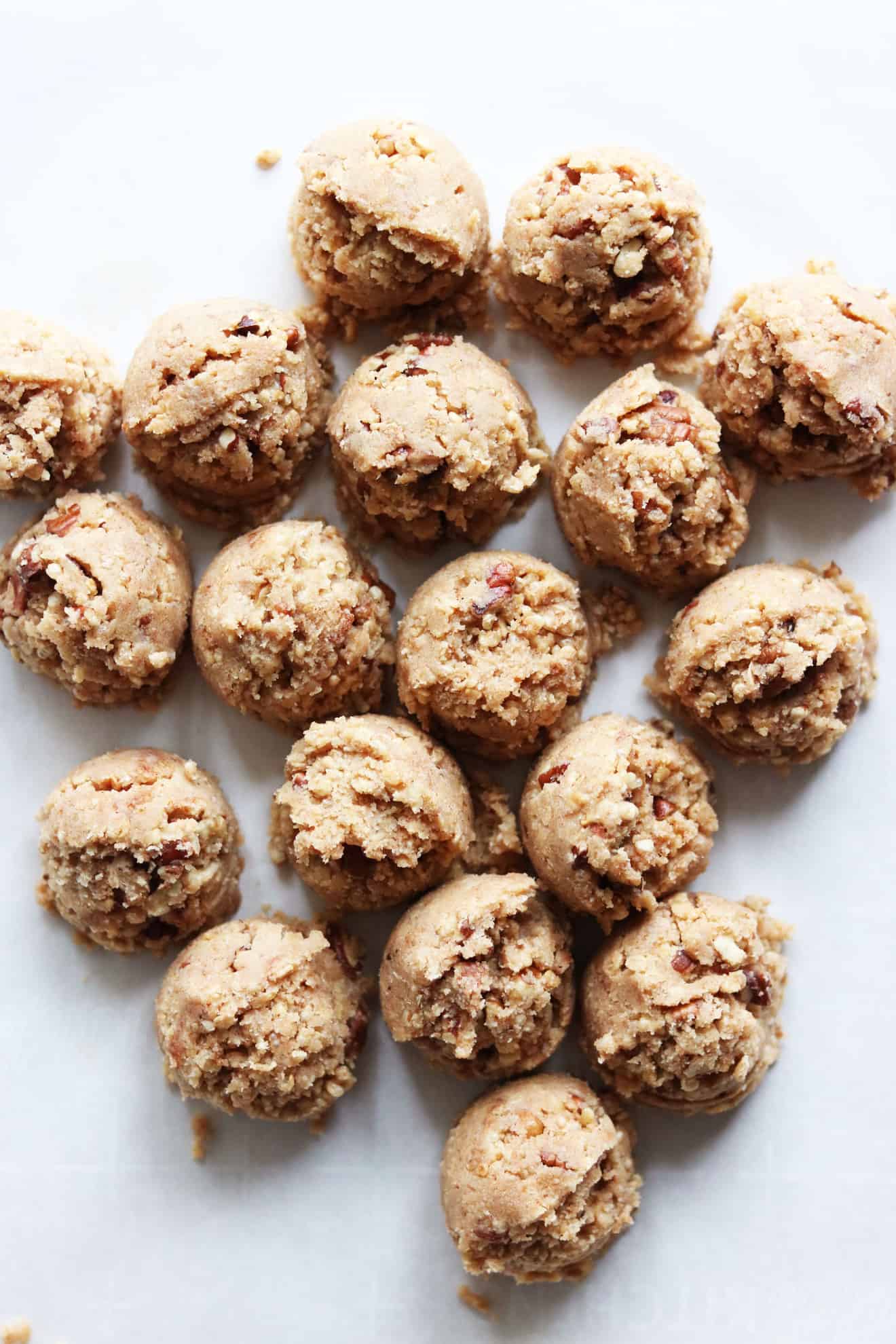 Gingerbread Bliss Balls scooped out on a white counter before they are rolled and dipped in chocolate