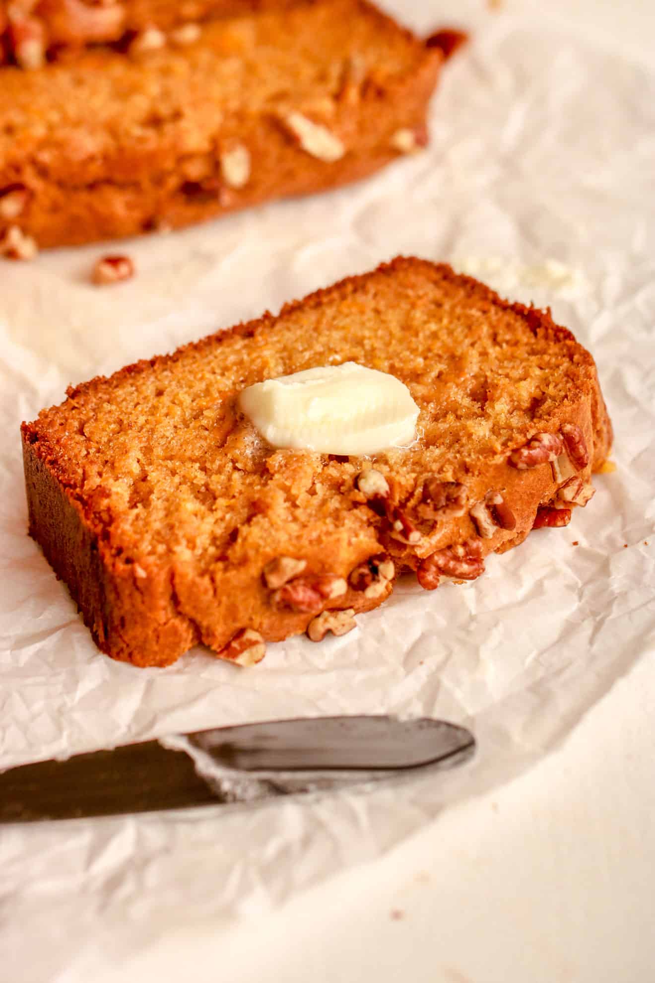 sweet potato bread with a melted pad of butter on parchment paper