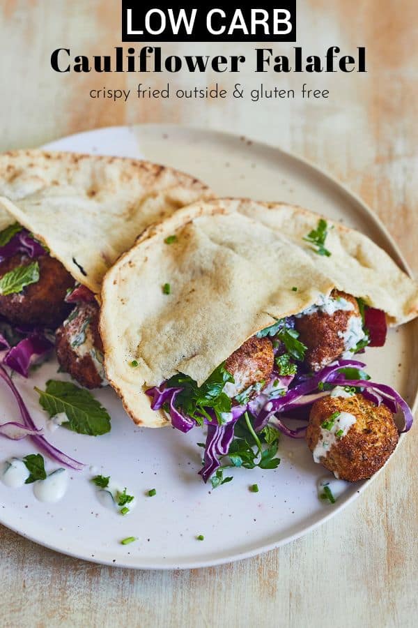 cauliflower falafel with cabbage, herbs and tzatziki in pita on white plate on cutting board pinterest image