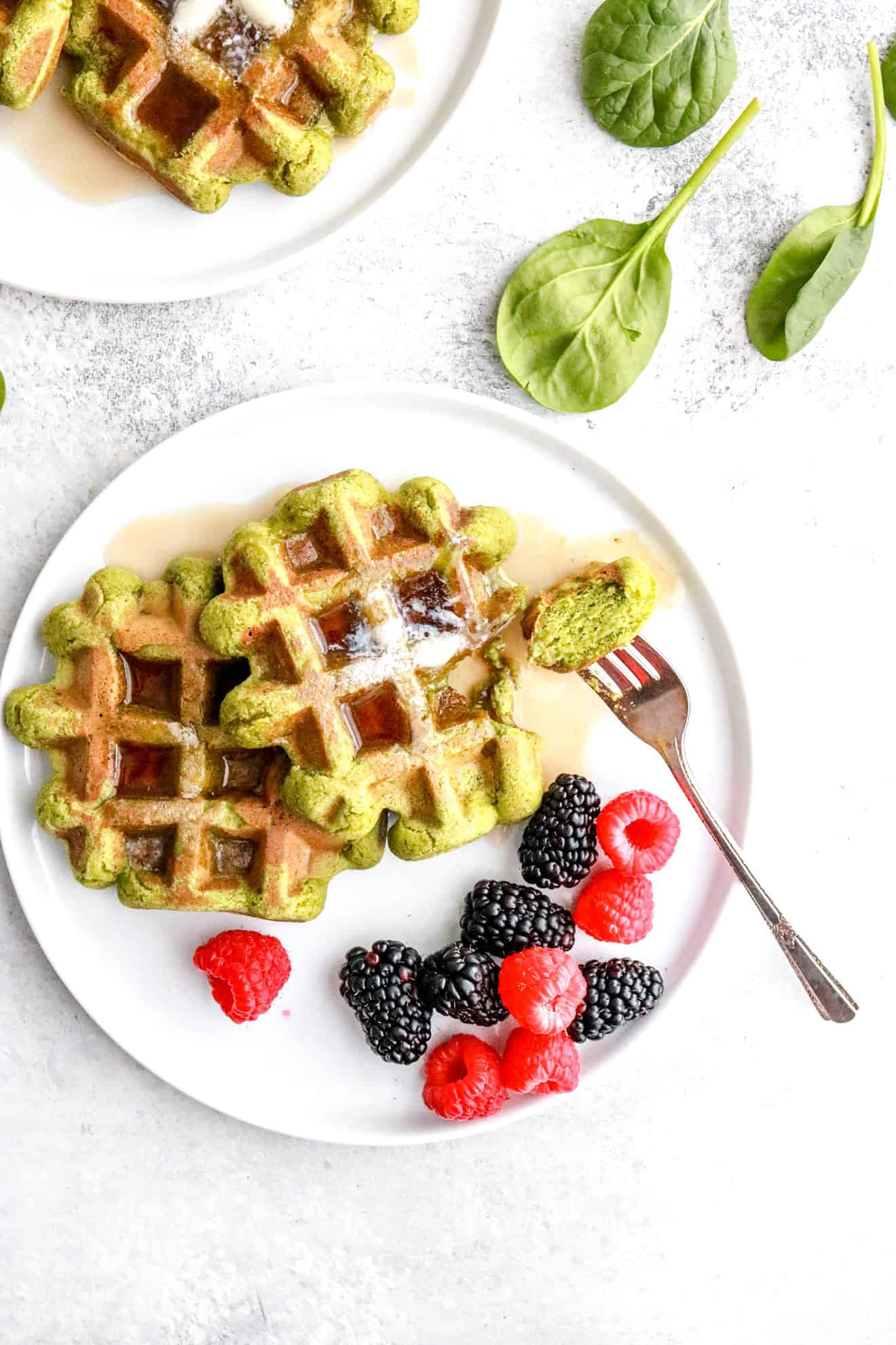 green spinach waffles with butter and syrup on white plate and white background