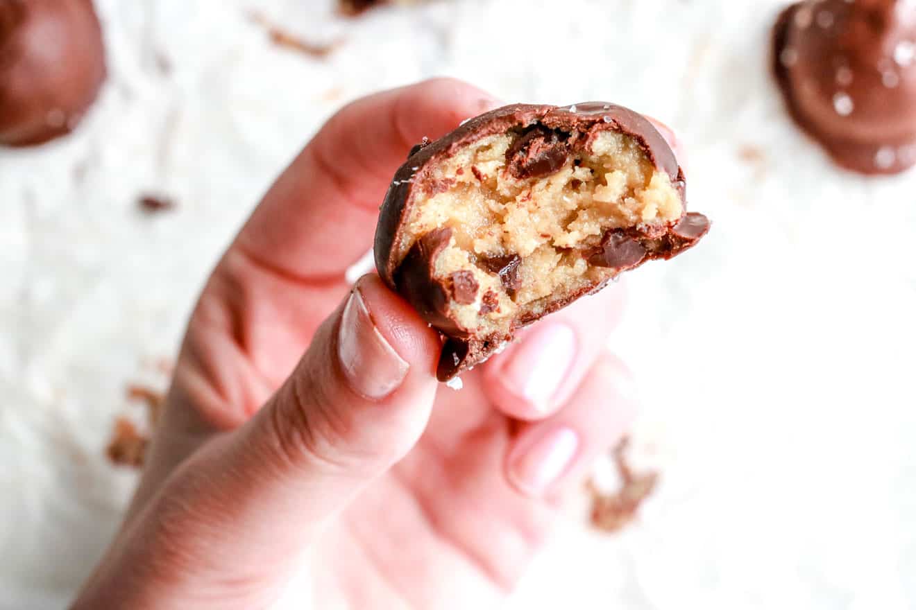 hand holding No Bake Tahini Cookie Dough Truffles with white background