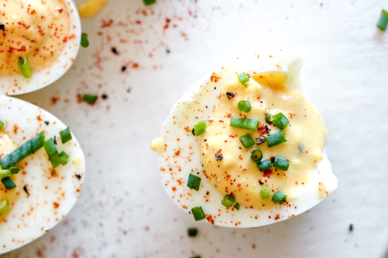deviled egg with bite taken out of it with paprika and chopped chives on top