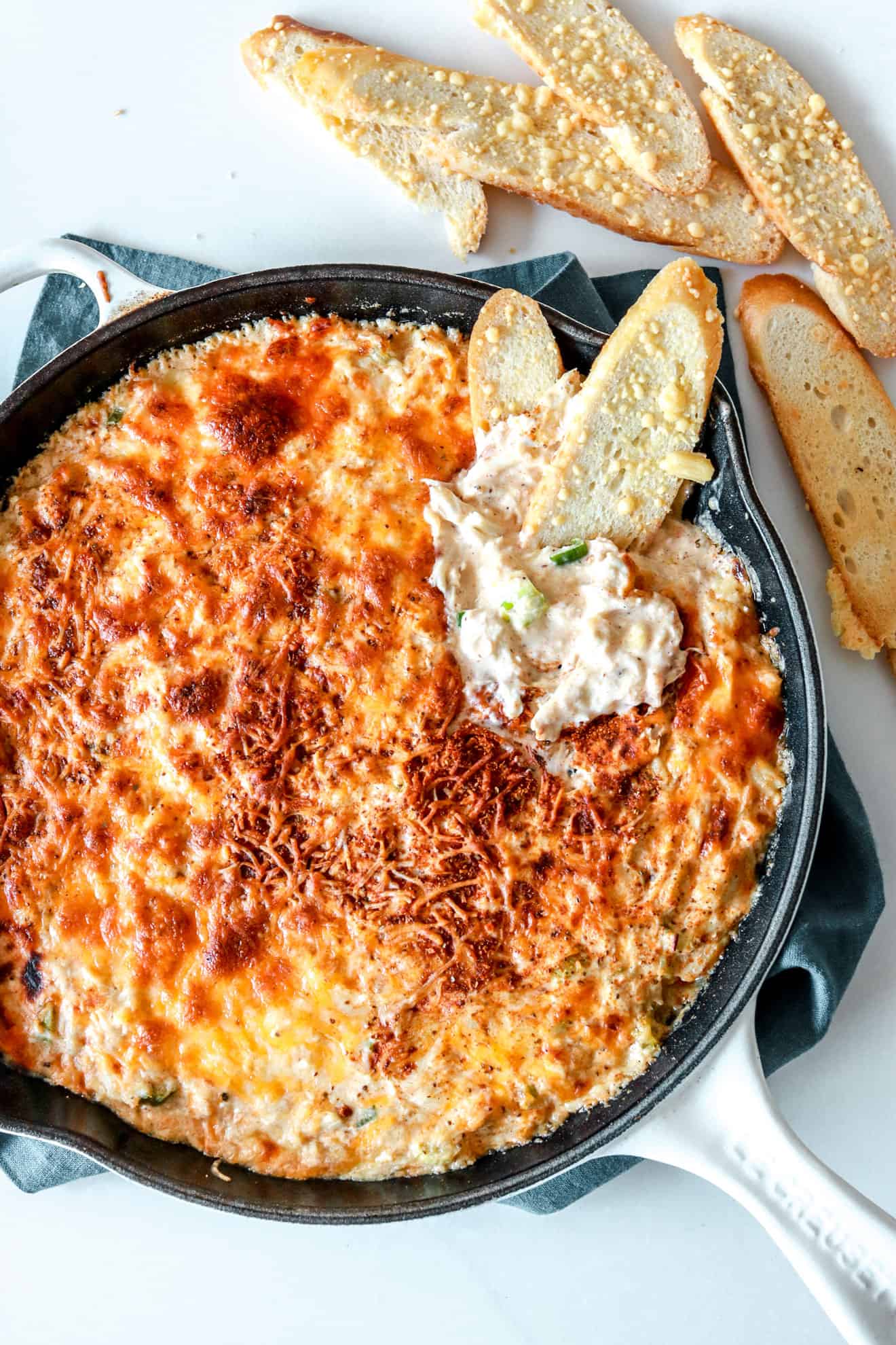 overhead image of a skillet filled with hot crab dip and bread on the side