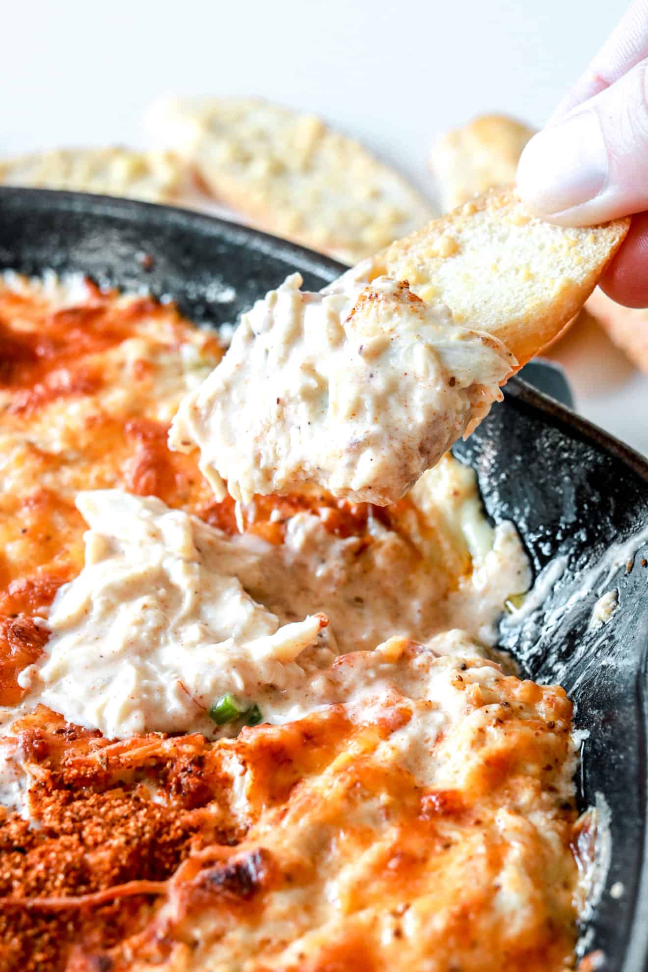 close up image of bread dipping into hot crab dip