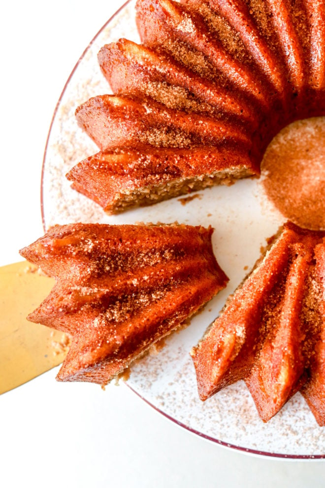 overhead view of apple cider bundt cake with slice being cut from the cake on a gold pie slicer