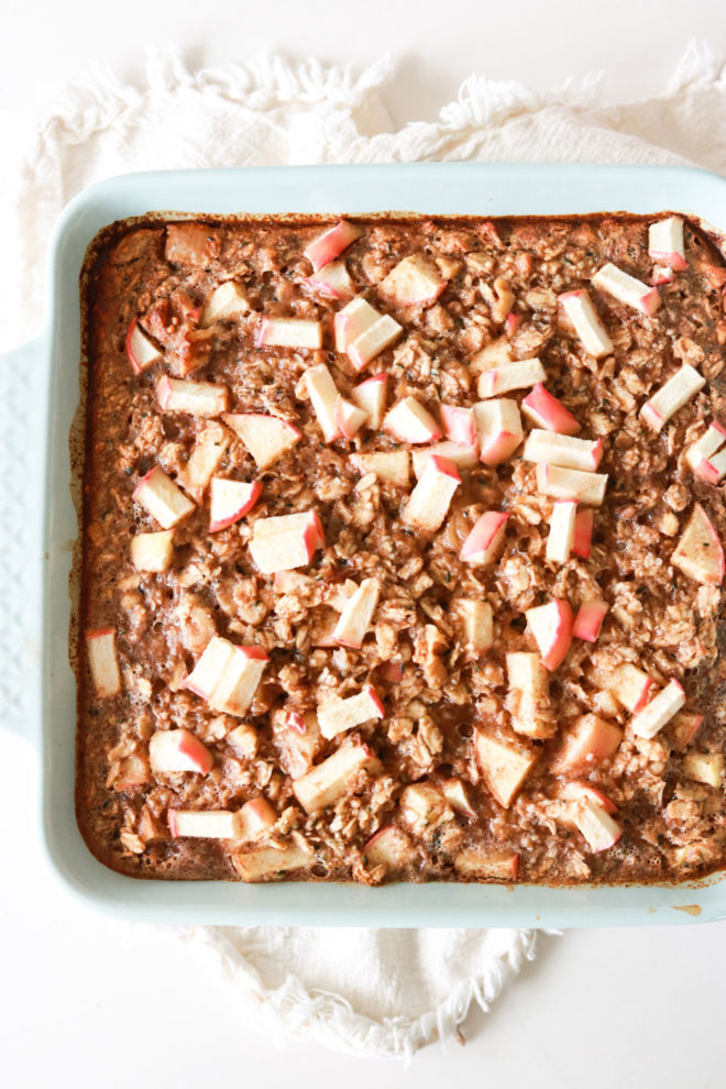 light blue square baking dish with baked apple cinnamon oatmeal on a white counter