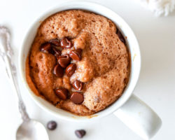 white mug filled with chocolate chip cookie mug cake on white counter