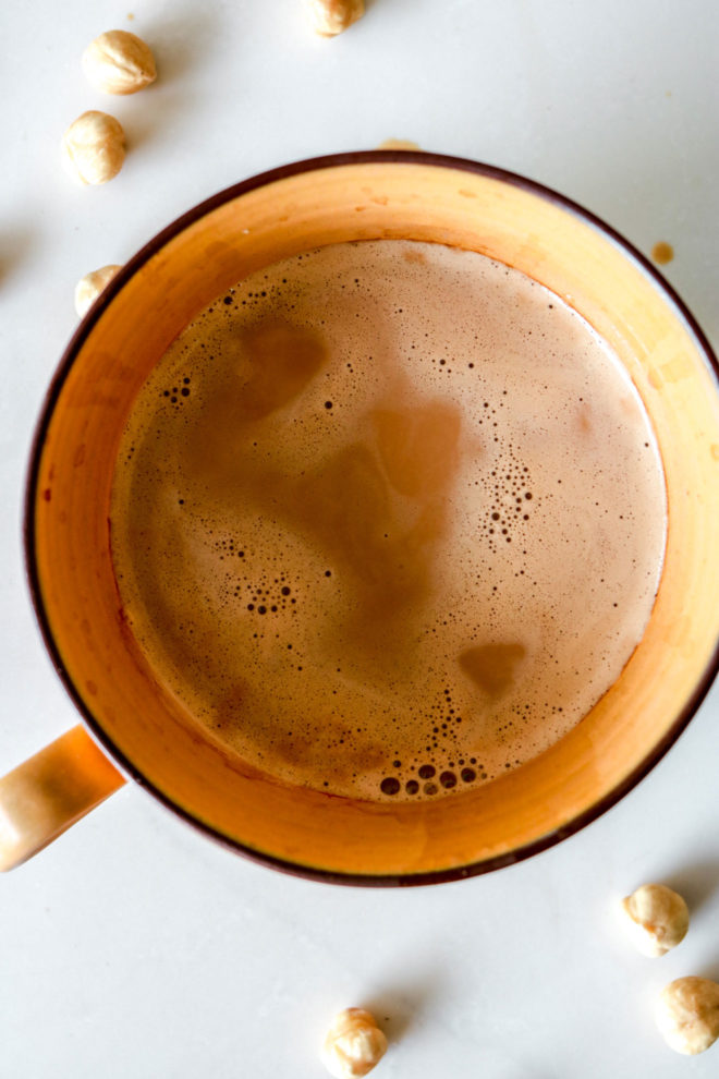 overhead image of a yellow mug with hazelnut coffee inside