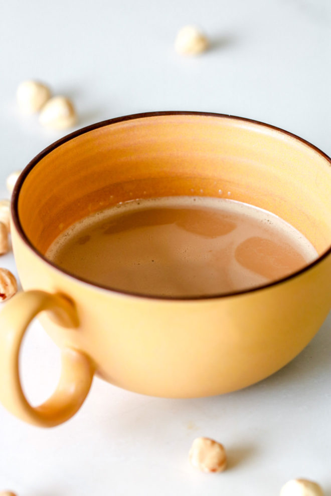 side image of a yellow mug with hazelnut coffee inside