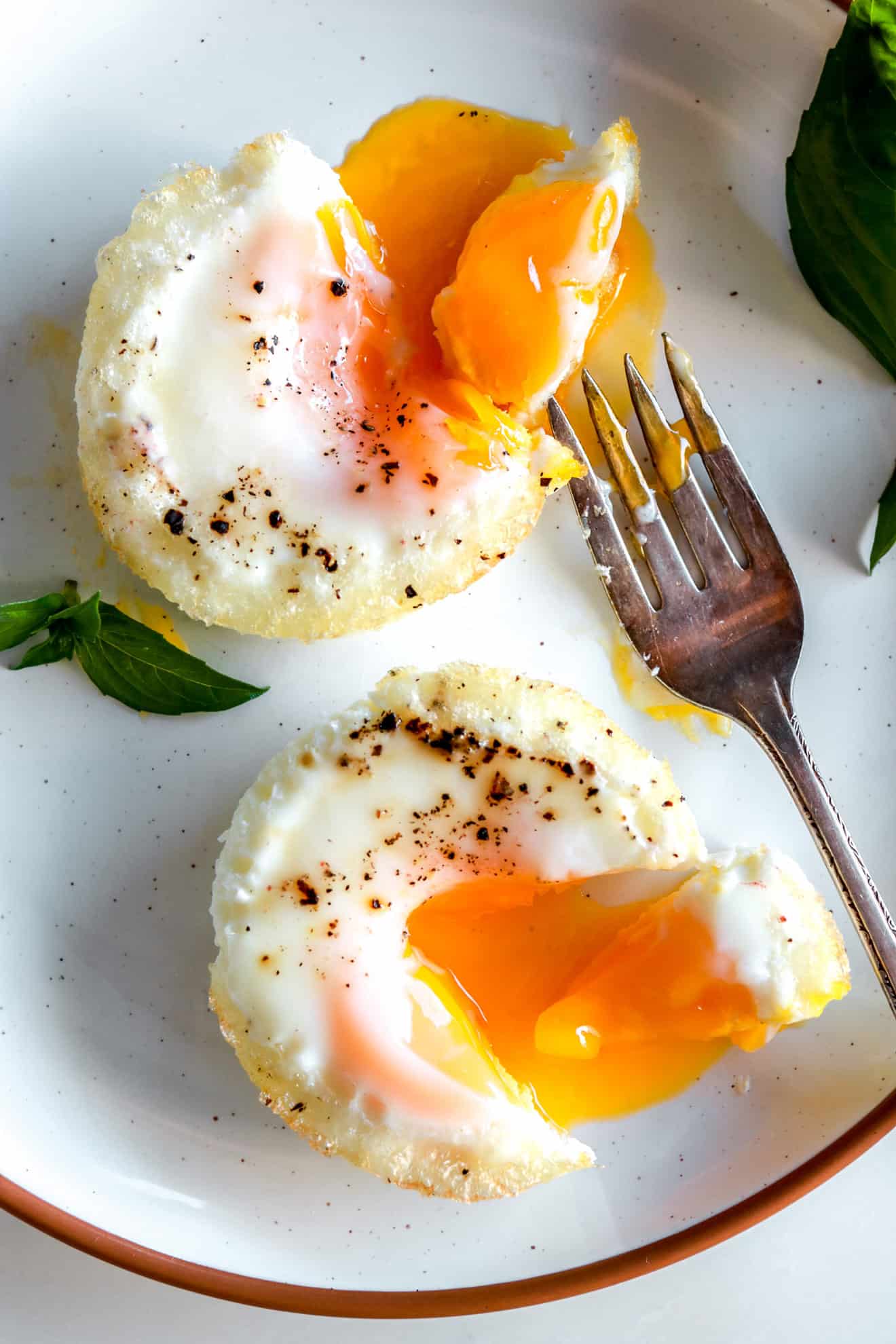plate with two oven-baked eggs with drippy yolks and a fork