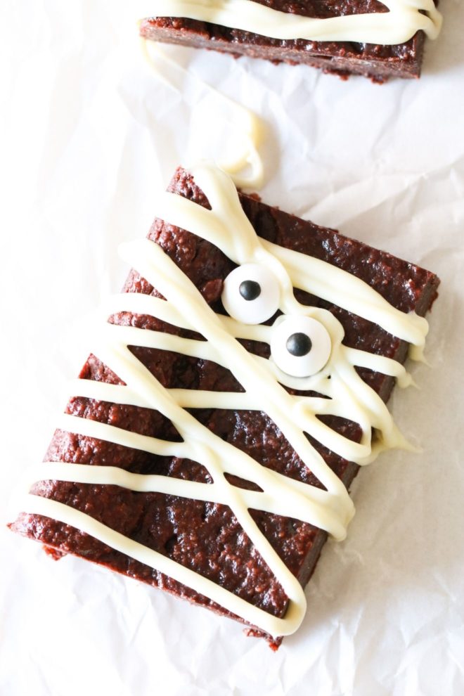 fudgey gluten free brownies with white chocolate and candy eyeballs decorating them to look like a mummy