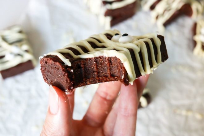 hand holding a gluten free brownie decorated as a mummy with a bite taken out of it