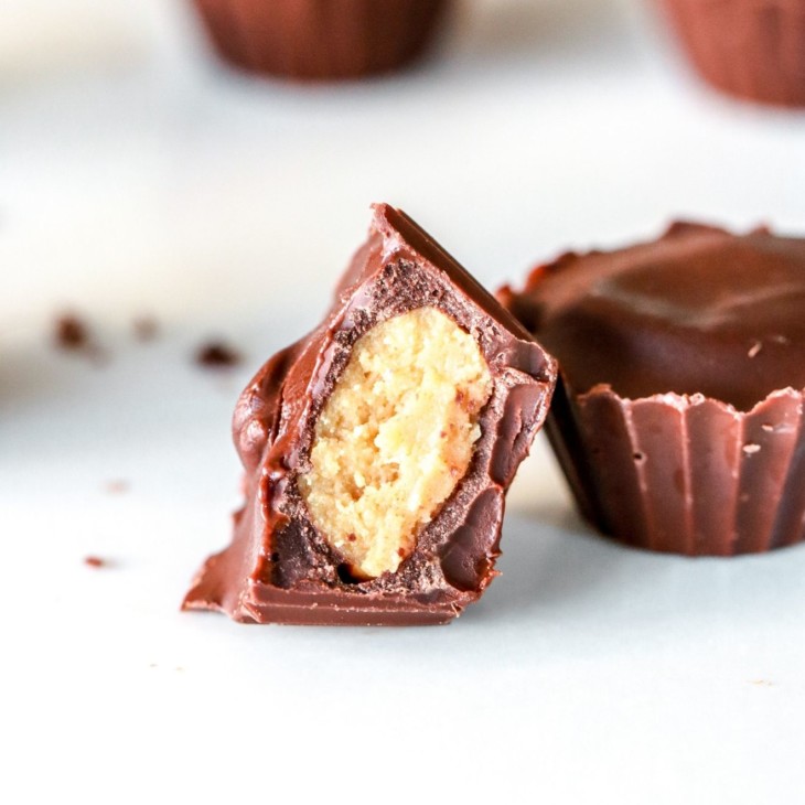 side angle of chocolate peanut butter cups, one leaning against the other with a bite taken out