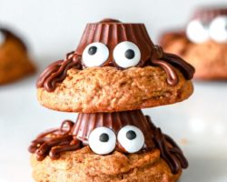 two peanut butter cookies decorated like spiders with legs and candy eyeballs, one cookie stacked on top of the other