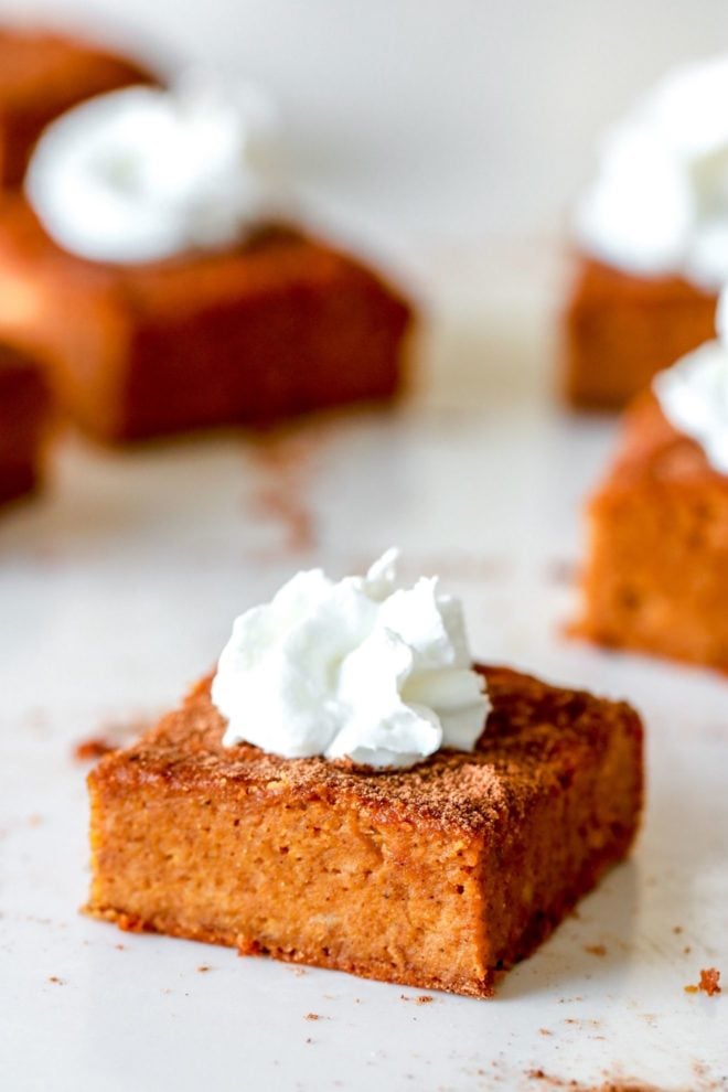 side view of a pumpkin banana cake bar with a dollop of whipped cream on top