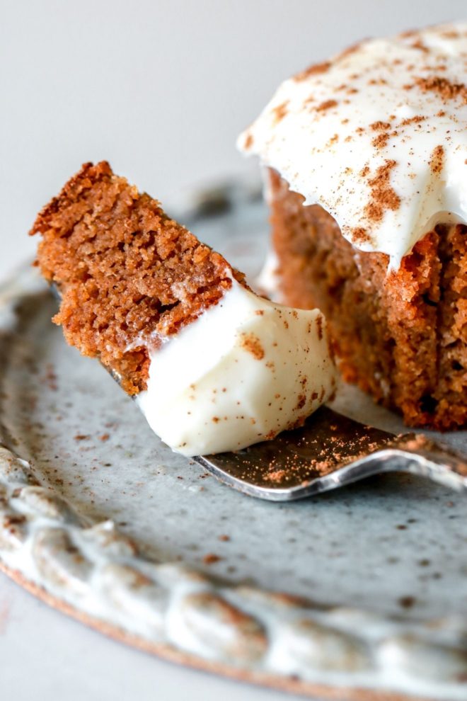close up image of a fork with a bite of pumpkin cake with cream cheese frosting