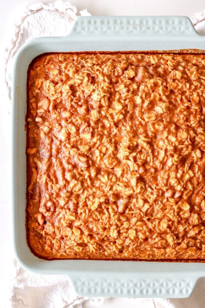 overhead image of a light blue baking dish on a white counter with pumpkin oatmeal in it