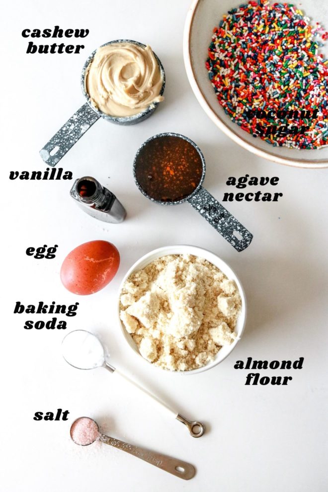 overhead image of ingredients to make cashew butter sprinkle cookies laid out on a white counter