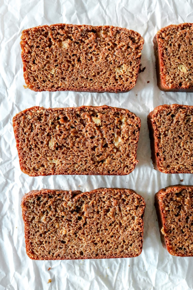 overhead image of slices of gingerbread banana bread on a wrinkled white piece of parchment paper