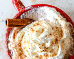 overhead image of a red mug with a hot beverage and whipped cream inside, a cinnamon stick sticking out. text overlay "simple & delicious gingerbread hot cocoa"
