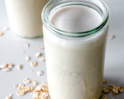 weck jar filled with oat milk on a white counter with oats scattered around it