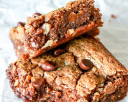 overhead image of a peanut butter bar leaning against another cookie bar with a bite taken out of it. both bars sit on a wrinkled piece of parchment paper.