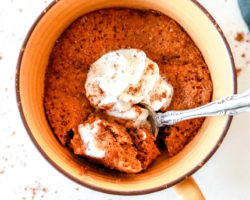 overhead image of a yellow mug with a baked pumpkin cake and a spoon digging in