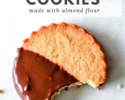 overhead image of a circle shortbread cookie half dipped in chocolate with a bite taken out and laying on a white counter with text overlay "gluten free shortbread cookies made with almond flour"