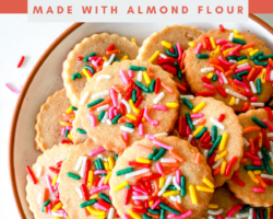 overhead image of a plate on a white counter. the plate has shortbread sprinkle cookies on it. rainbow sprinkles are scattered on the counter. text overlay reads "gluten free shortbread cookies made with almond flour"