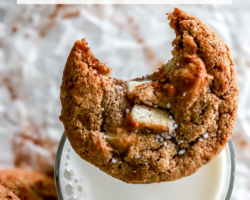 This is an overhead image of a glass of milk with a cookie on top. The cookie has a bite taken out of it with chocolate chunks and salt on top. Text overlay reads "chewy white chocolate ginger snap cookies"