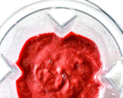 This is an overhead image looking into a blender with cherry smoothie inside. The blender sits on a white counter. Text overlay reads "healthy cherry smoothie only 5 ingredients!"