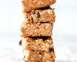 This is an image of a stack of chocolate chop granola bars on a white piece of parchment paper and white background.