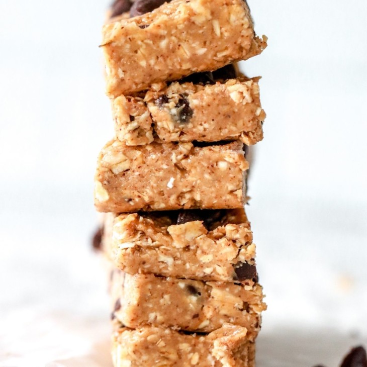 This is an image of a stack of chocolate chop granola bars on a white piece of parchment paper and white background.