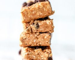 This is an image of a stack of chocolate chop granola bars on a white piece of parchment paper and white background. Text overlay reads "vegan & gluten free granola bars."