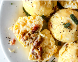 This is an image of a white plate with egg bites on it. One egg bite is cut open and cheese and bacon is inside. The egg bites are topped with chopped sage and ground pepper. text overlay reads "instant pot egg bites".