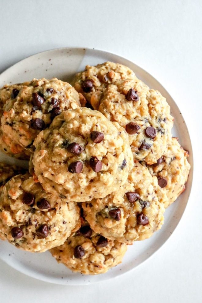 This is an overhead image of a plate of oatmeal chocolate chip cookies. The plate is on a white counter.