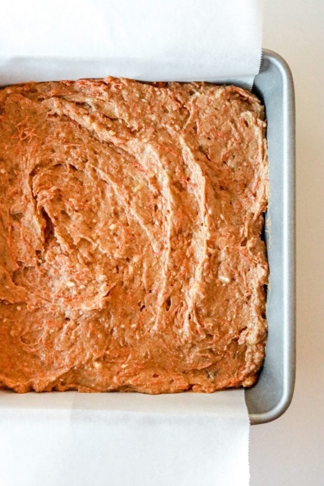 This is an overhead image of a square pan with carrot cake spread out in an even layer across the bottom.