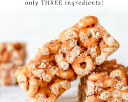 This is a side view of a cheerio bar leaning against another bar. More cereal bars are blurred in the background. The bars sit on a white surface with a white background. Text overlay reads "peanut butter cheerio bars only three ingredients!"