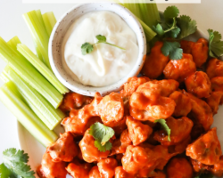 This is an overhead image of a plate with buffalo cauliflower florets. The plate also has a small bowl of blue cheese dip and celery sticks. Text overlay reads "buffalo cauliflower made in the air fryer"