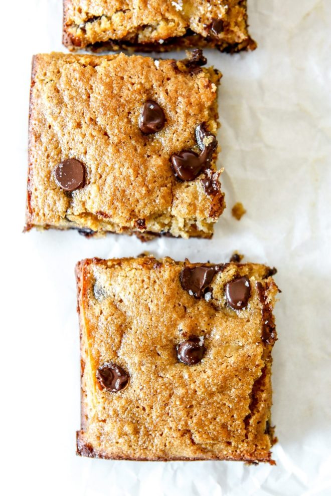 This is an overhead image of three banana bars with chocolate chips on top. The bars sit on a white background.