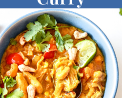This is an overhead image of a blue bowl filled with jackfruit curry. The curry is topped with lime, cilantro and cashews. A spoon is dipping into the curry and leaning against the side of the bowl. The bowl sits on a white counter with cilantro leaves scattered around it. Another blue bowl filled with curry is in the bottom left of the image. Text overlay reads "healthy jackfruit curry."