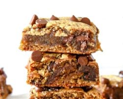 This is a stack of three tahini bars. The stack sits on a white parchment paper with a white background and more tahini bars blurred in the background.