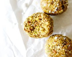 This is an overhead image of pistachio energy balls on a white piece of parchment paper. One energy ball has a bite taken out of it.