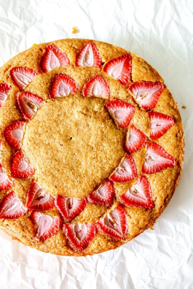 This is an overhead image of strawberry lemon cake. The cake sits on a white piece of parchment paper.