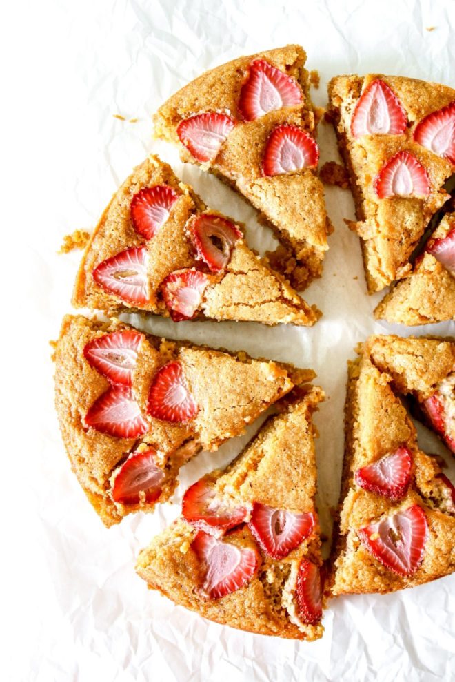This is an overhead image of sliced strawberry lemon cake. The cake slices are slightly pulled apart and are sitting on a white piece of parchment paper.